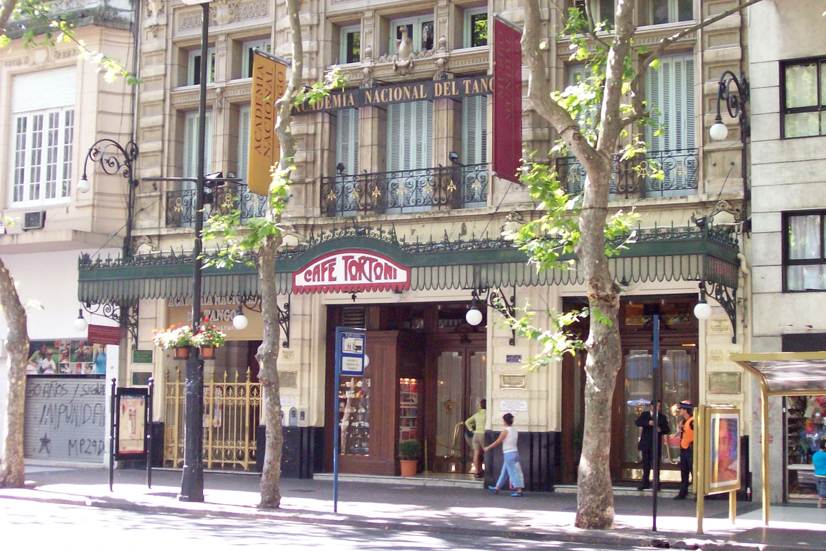 Friends talking around a café table in Buenos Aires, with the street visible through the window