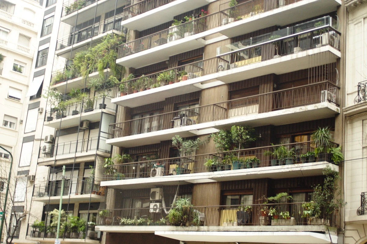 Apartment balconies and a residential entrance on a tree-lined Buenos Aires street